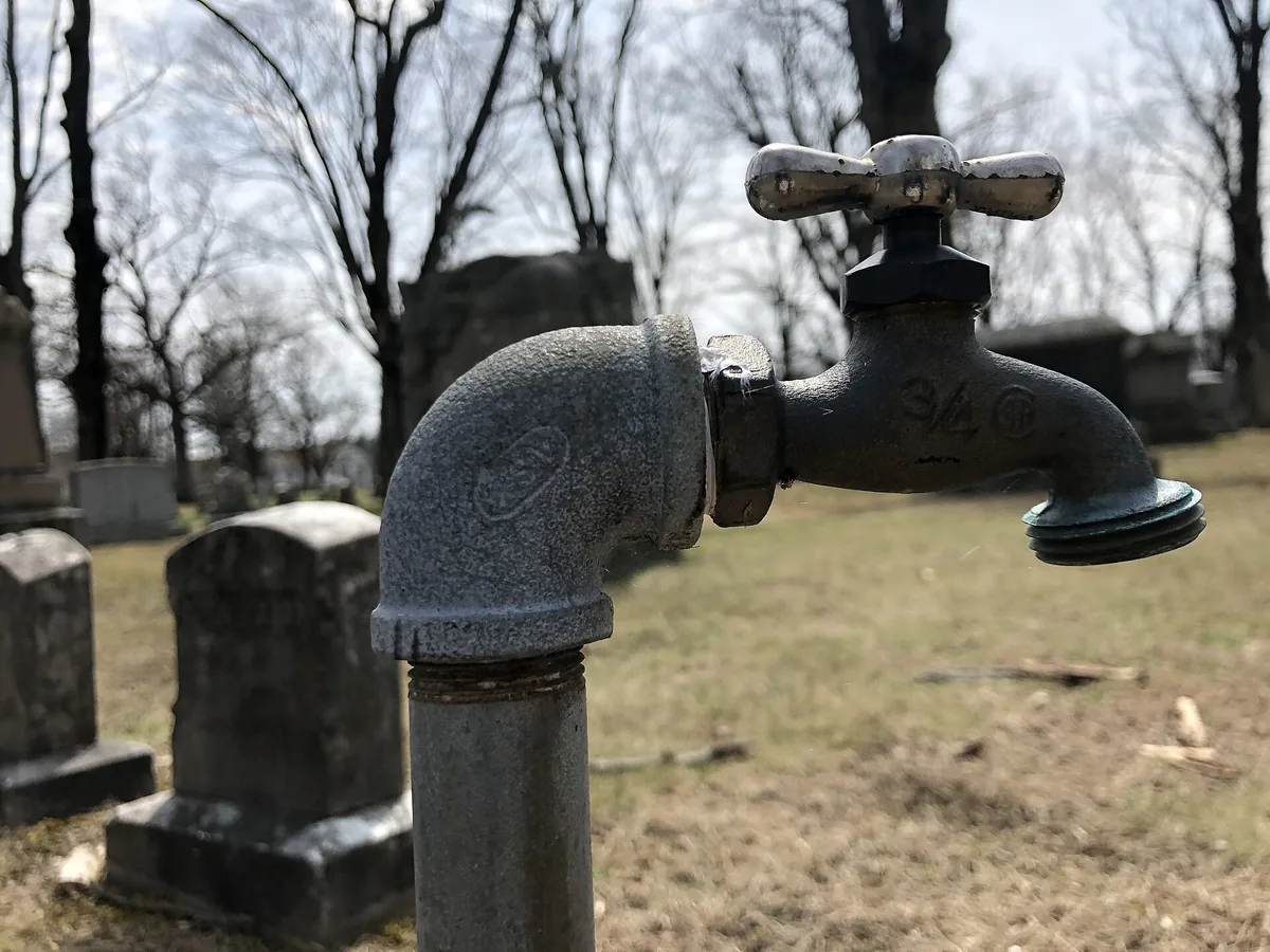 Outdoor spigot with water pooled beneath it on frozen ground