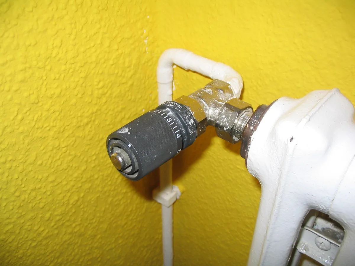 Close-up of fingers turning a thermostatic radiator valve counterclockwise