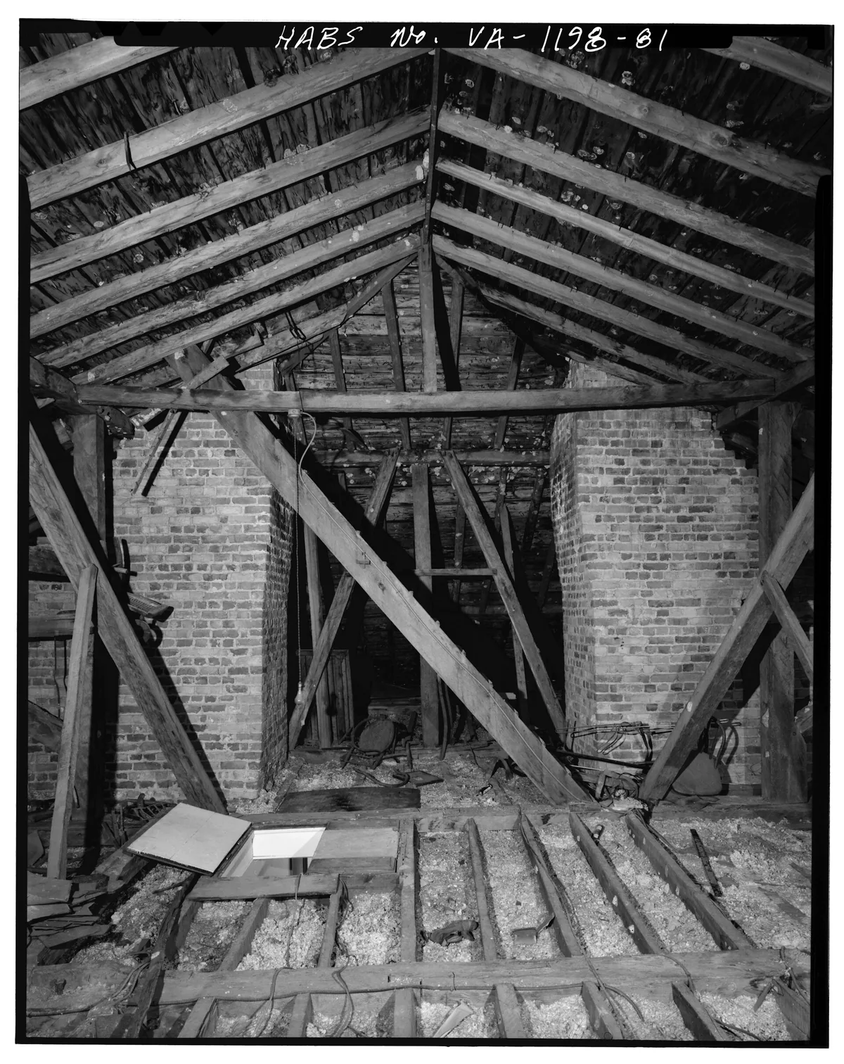 An attic hatch in a hallway ceiling, slightly ajar