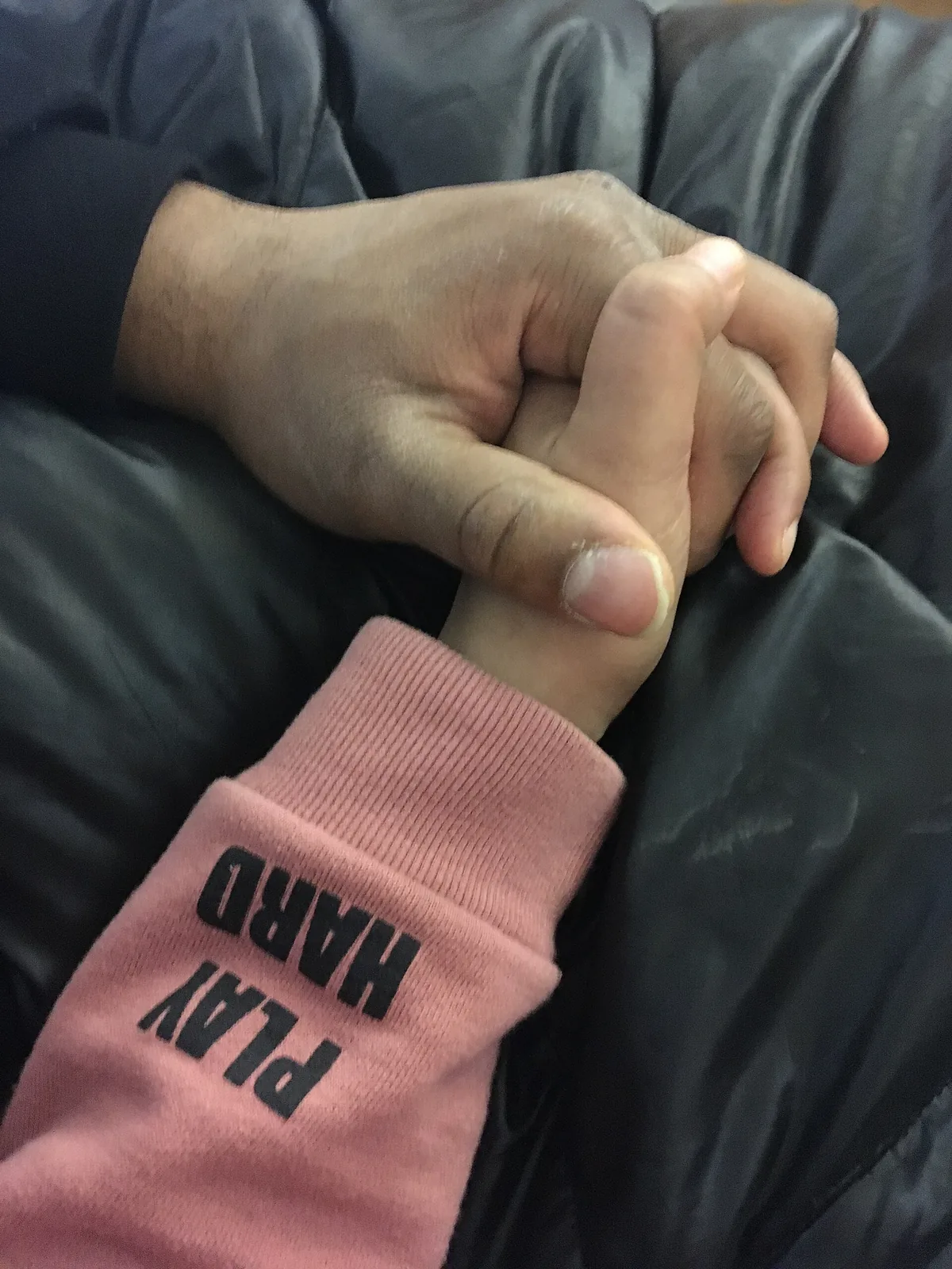 Hand holding a bottle of enzyme drain cleaner next to an open under-sink cabinet